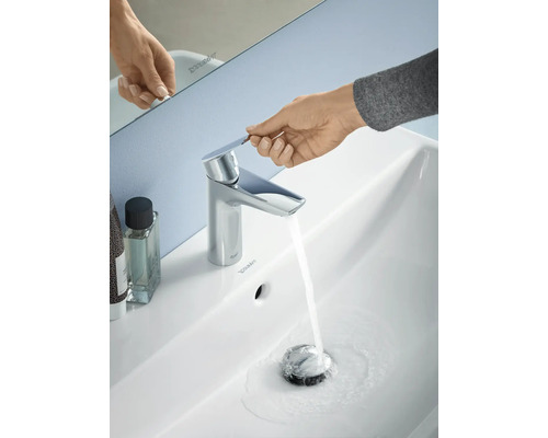 Aufnahme eines Waschbeckens mit laufendem Wasserhahn und einer Hand, die den Wasserhahn bedient