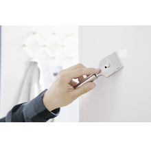 Eine Person entfernt mit einem Spachtel Farbreste von einer Wand.