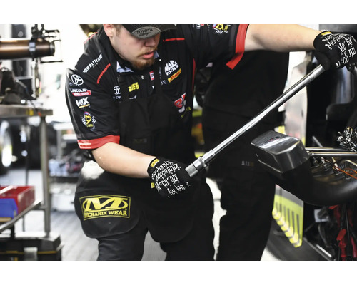 Ein Mechaniker arbeitet mit einem Werkzeug. Er trägt Mechanix Wear Handschuhe und Mechanix Wear Hose.