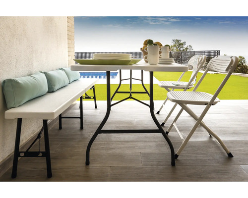 Szene mit Klapptisch, Klappstühlen und Bank mit Kissen auf einer Terrasse