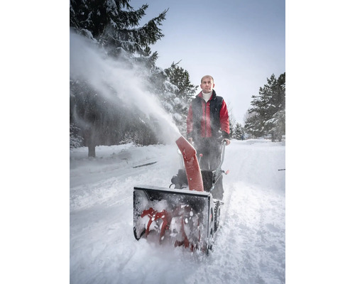 Mann benutzt eine Schneefräse zum Schneeräumen auf einer schneebedeckten Straße
