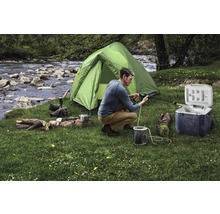 Szene einer Campingausrüstung mit Zelt, Kühlbox, Feuerholz und Person bei der Reinigung