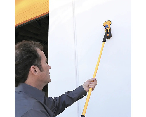 Mann verwendet einen Multifunktionsdetektor mit Teleskopstiel an einer Wand.