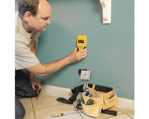Mann verwendet einen gelben Wandscanner zur Ortung von Objekten in einer Wand.