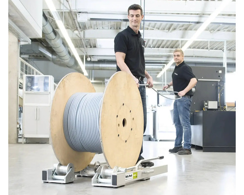 Mitarbeiter ziehen ein Kabel von einer Kabeltrommel auf einem Rollwagen.