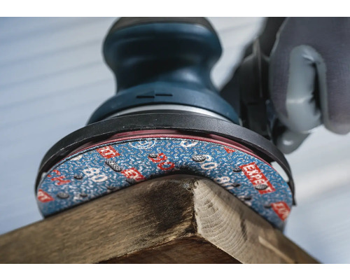 Ein Schwingschleifer schleift ein Holzstück.