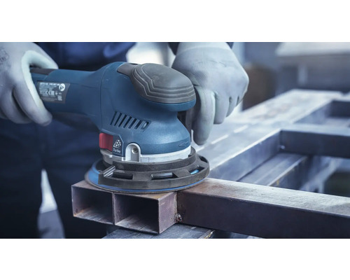 Eine Person schleift mit einem Exzenterschleifer ein Metallstück.