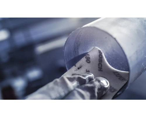 Hand schleift zylindrisches Objekt mit Schleifpapier der Körnung 180