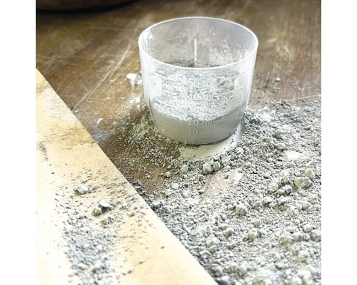 Messbecher mit Zement auf einer Holzoberfläche