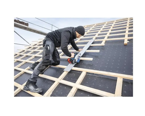 Ein Handwerker sägt mit einer Handkreissäge auf einem Dach.