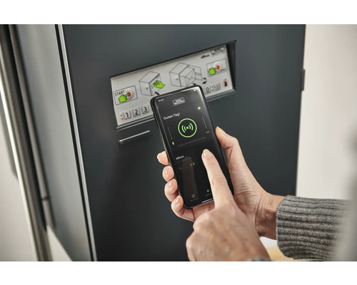 Eine Person bedient eine Paketbox mit einem Smartphone.