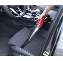 Eine Person saugt mit einem Handstaubsauger das Innere eines Autos