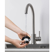 Eine Person reinigt einen Staubsaugerfilter unter einem Wasserhahn