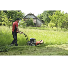 Mann mäht hohes Gras mit einem Balkenmäher in einem Garten.