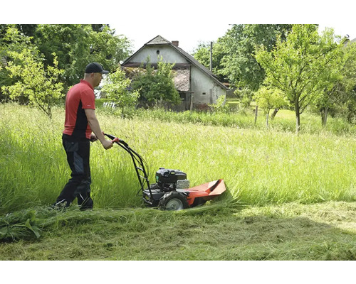 Mann mäht hohes Gras mit einem Balkenmäher in einem Garten.