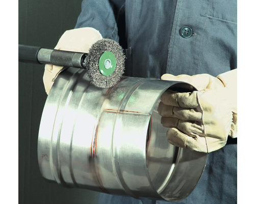 Eine Person reinigt ein Metallrohr mit einer Drahtbürste.