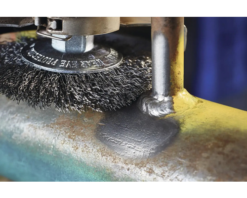 Drahtbürste entfernt Rost von einem Metallrohr