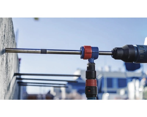 Eine Bohrmaschine bohrt ein Loch in eine Betonwand mit einer Bohrstaubabsaugung