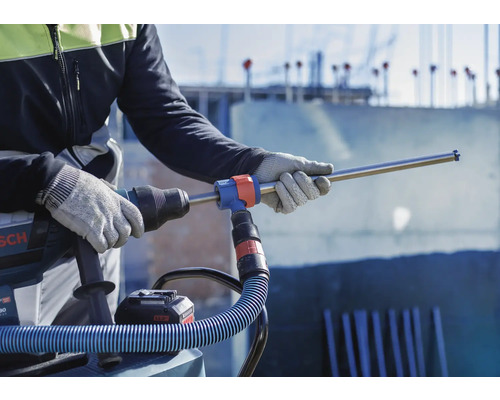 Handwerker mit Bohrhammer und Staubsauger für staubfreies Bohren auf einer Baustelle