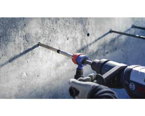 Eine Bohrmaschine bohrt mit einem Bohrer ein Loch in eine Betonwand.