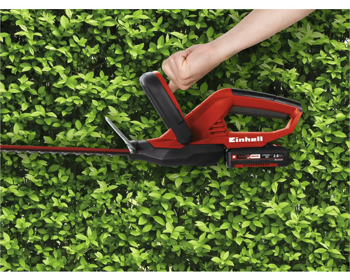 Einhell Akku Heckenschere im Einsatz vor grüner Hecke