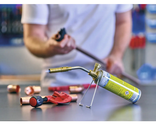 Lötlampe mit Kupferrohren und Rohrabschneider auf einer Werkbank