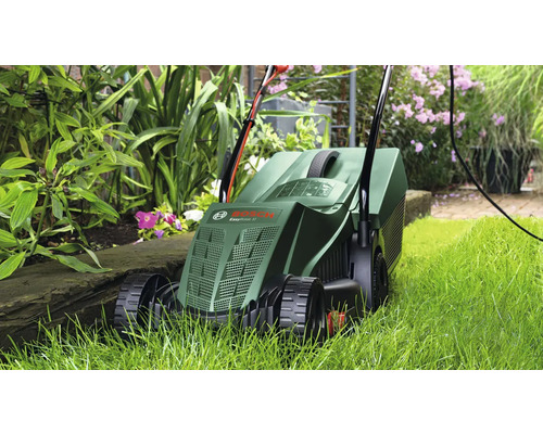 Rasenmäher im Einsatz im Garten zwischen Pflanzen