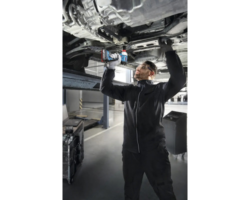 Ein Mechaniker arbeitet mit einem Akku-Schlagschrauber an einem Auto auf einer Hebebühne.