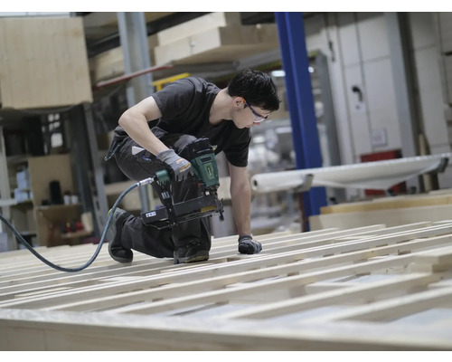 Handwerker befestigt Holzlatten mit einem Druckluftnagler
