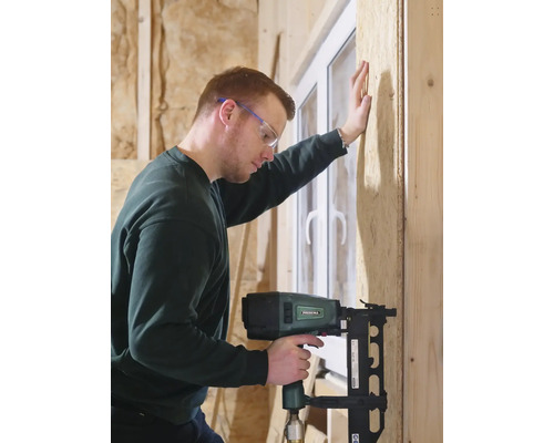 Handwerker befestigt Holzplatte mit Druckluftnagler