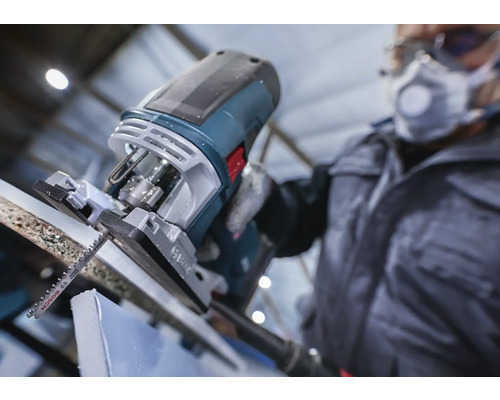 Eine Stichsäge schneidet ein Werkstück, bedient von einer Person mit Schutzkleidung.