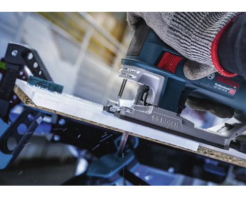 Nahaufnahme einer Stichsäge beim Schneiden eines Werkstücks, bedient von einer Person mit Handschuhen.