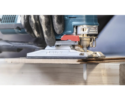 Nahaufnahme einer Stichsäge beim Schneiden von Holz mit Handschuhen für Heimwerker.