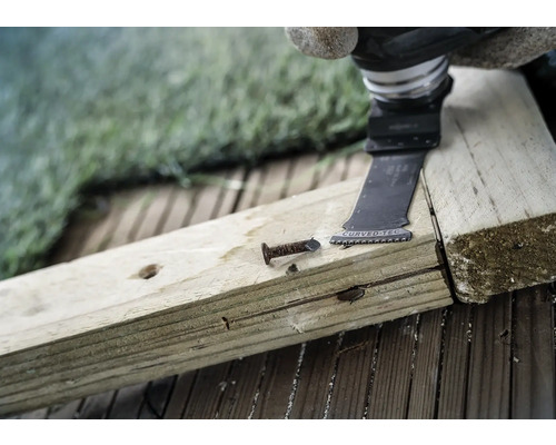 Oszillierendes Elektrowerkzeug schneidet einen Nagel in einem Holzbrett.