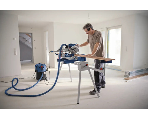 Mann schneidet Holz mit einer Kapp- und Gehrungssäge in einem hellen Raum