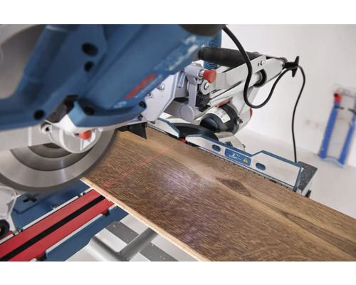 Kapp- und Gehrungssäge schneidet ein Holzbrett mit Laserführung.