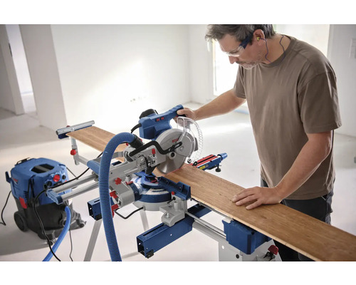 Mann bedient eine Bosch Kapp- und Gehrungssäge mit Werkstück und Staubsauger