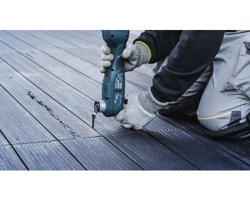 Eine Person arbeitet mit einem Multifunktionswerkzeug an einer Holzterrasse.