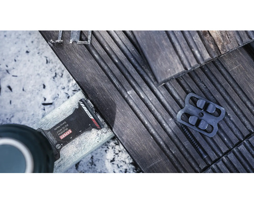 Bosch Logo. Detailaufnahme eines Multitools beim Kürzen von Terrassendielen.