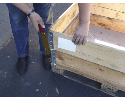 Eine Person befestigt eine Holzpalette mit einem Schraubendreher.