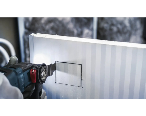 Eine oszillierende Säge schneidet in eine Dämmplatte.