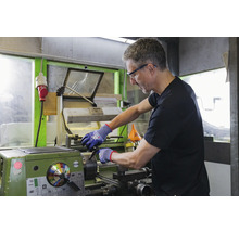 Ein Mann arbeitet an einer Drehmaschine in einer Werkstatt.