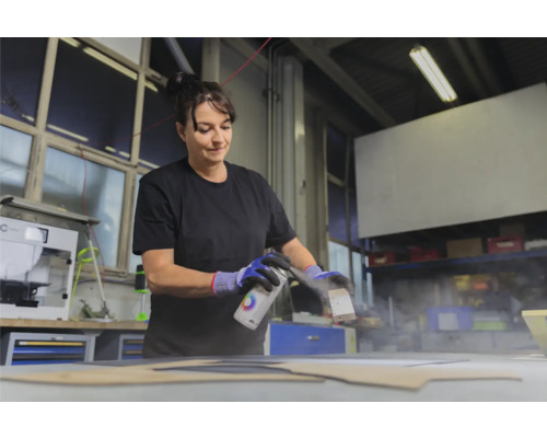 Frau sprüht Farbe auf ein Werkstück mit einer Farbsprühdose.