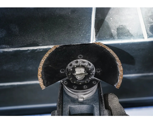 Oszillierendes Elektrowerkzeug schneidet Fugenmasse zwischen Fliesen