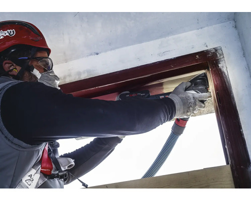 Handwerker renoviert Fensterrahmen mit einem Multifunktionswerkzeug