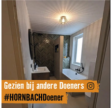 Helles Badezimmer mit Badewanne, Waschbecken und Wandfliesen im Fischgrätenmuster