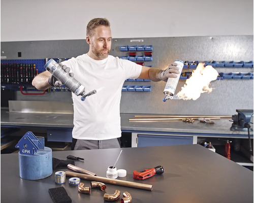 Mann beim Löten von Kupferrohren mit einem Gasbrenner