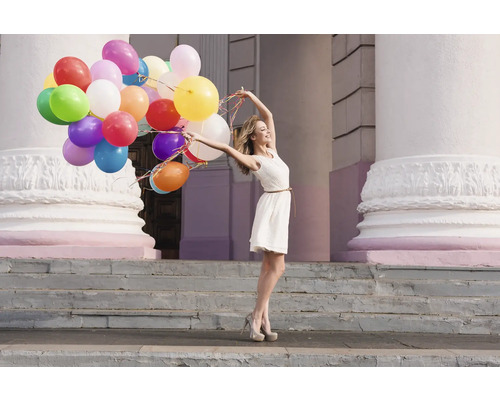 Frau mit vielen Ballons vor einem Gebäude