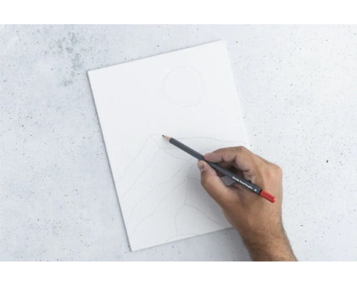 Hand zeichnet mit Bleistift eine Berglandschaft auf ein weißes Blatt Papier