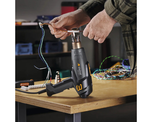Eine Person benutzt eine Heißluftpistole von Steinel, um Kabel zu bearbeiten.